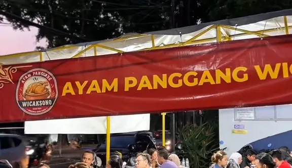 Pengunjung makan di bawah spanduk Ayam Panggang Wicaksono saat senja